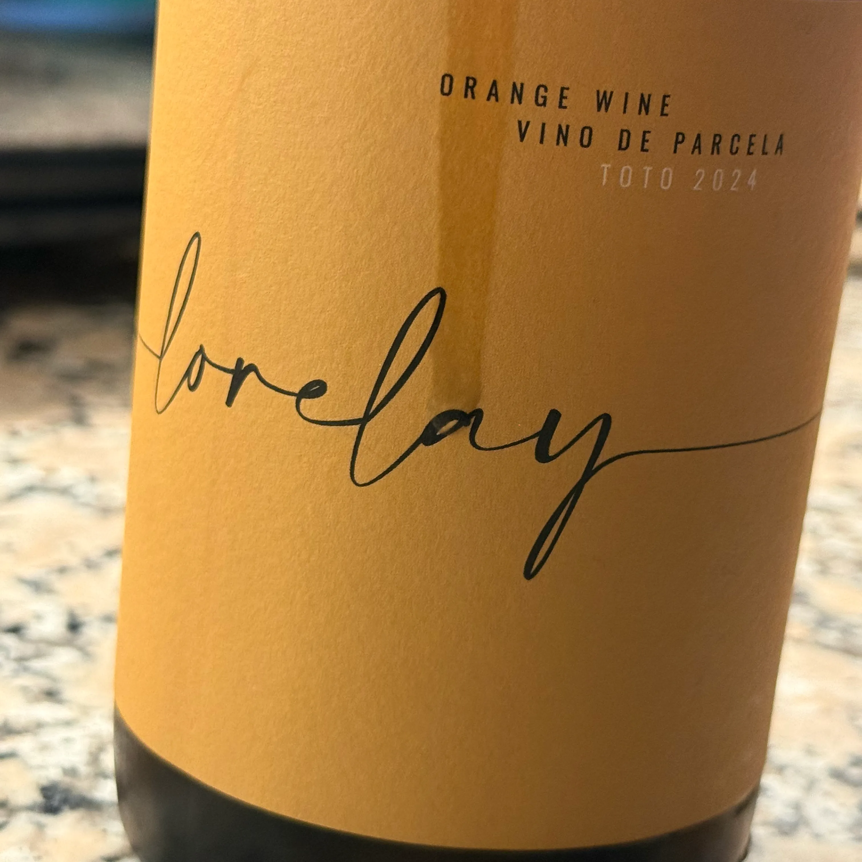 Botella del Lorelay Toto 2024, orange wine de listán blanco del Valle de Güímar, con su etiqueta color ámbar y el nombre manuscrito sobre una encimera de granito.